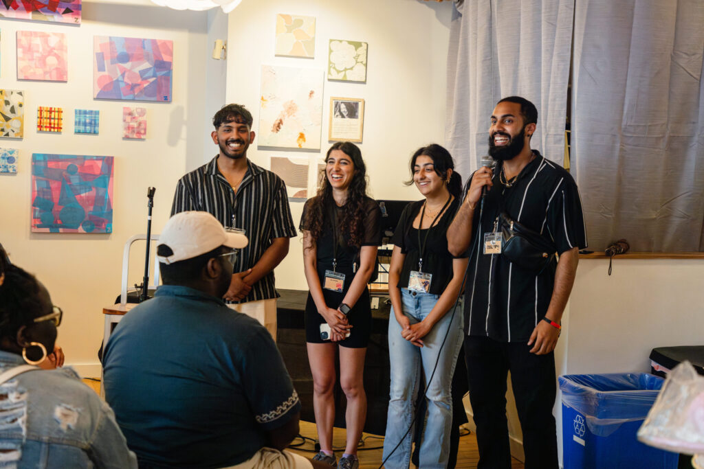 the four founders standing beside each other with the person on the furthest right holding a microphone